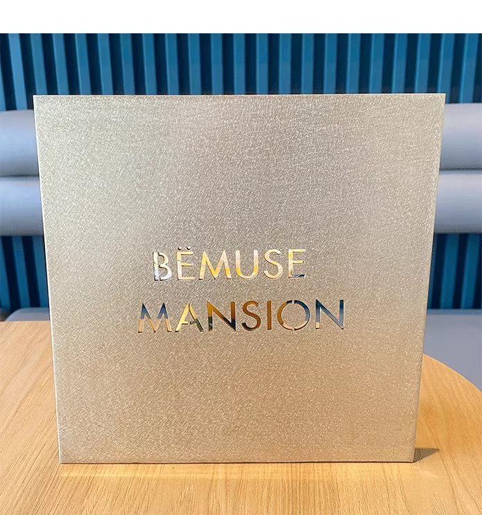 Close-up front view of a square brass plaque. Features precise laser-cut technology where the logo and text are cut through the metal, creating a sophisticated negative space effect.