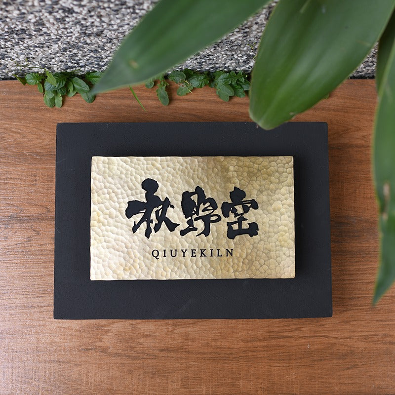 Close-up detail of hand-hammered brass texture and dark steel border.