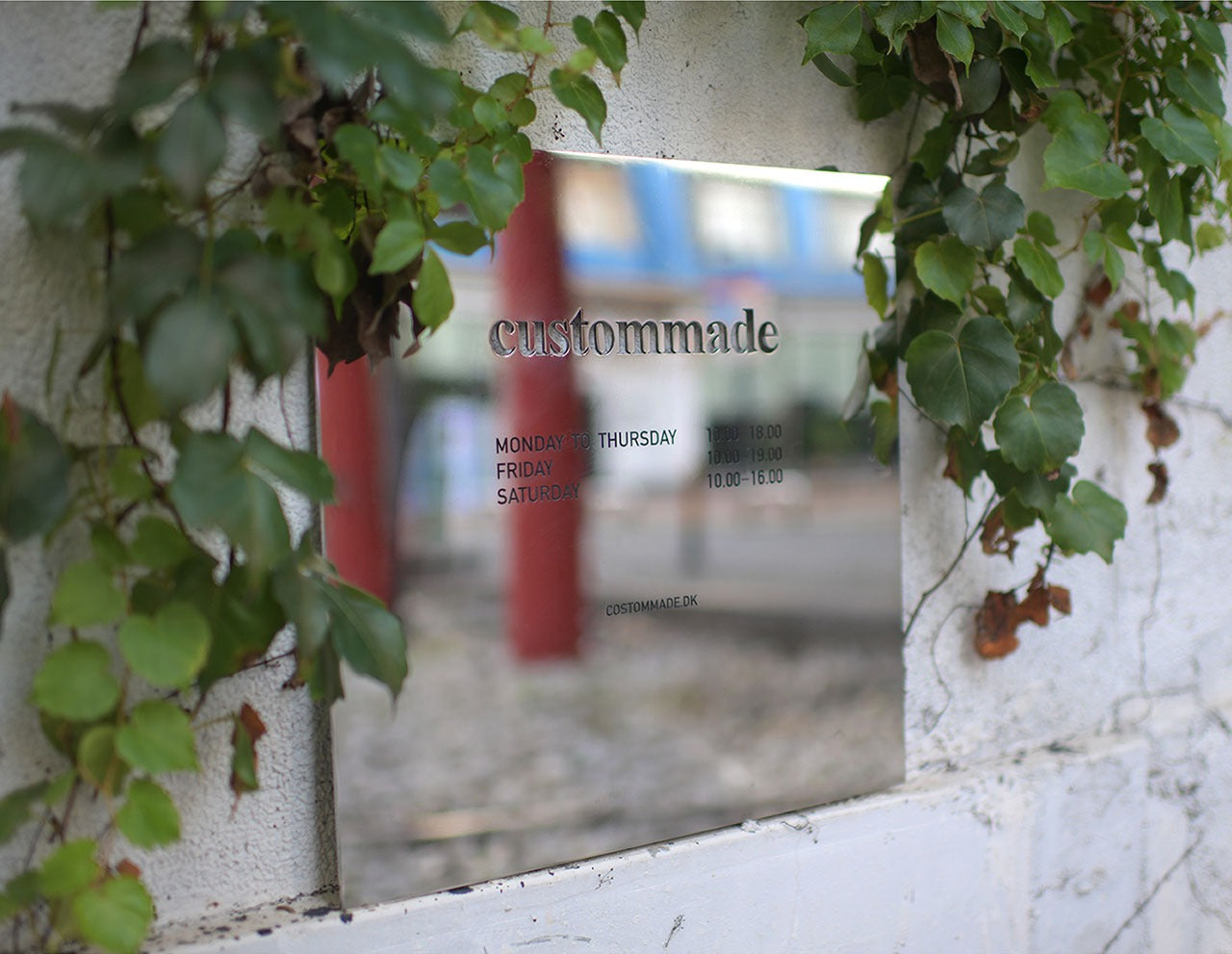 Outdoor mirror stainless steel sign surrounded by greenery, demonstrating the reflective surface blending seamlessly with nature