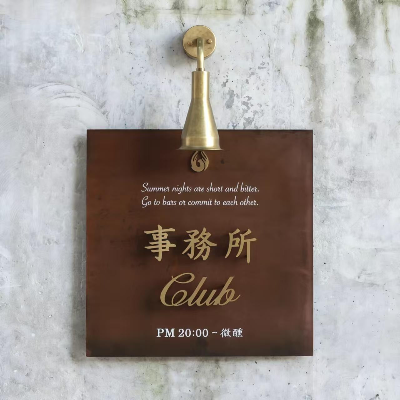 Vintage Rusted Iron Plaque Installed on Concrete Wall with Gooseneck Light.